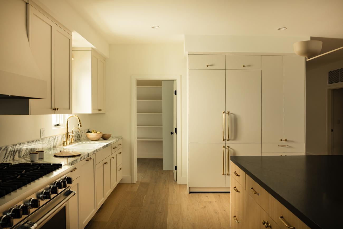 Galley kitchen with white oak cabinetry and honed black stone counters